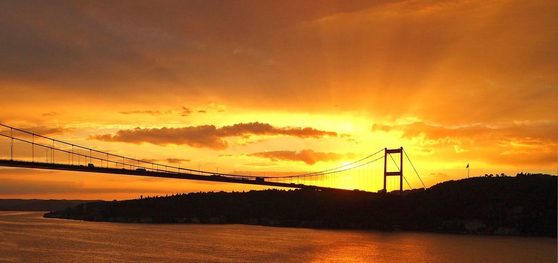 Fatih sultan mehmet bridge over river against cloudy sky during sunset