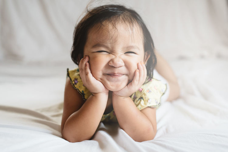 Portrait of cute baby girl lying on bed at home