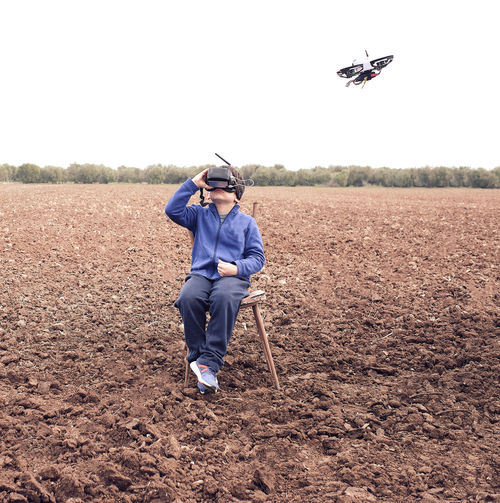 Boy watches with glasses the flight of the drone his father flies