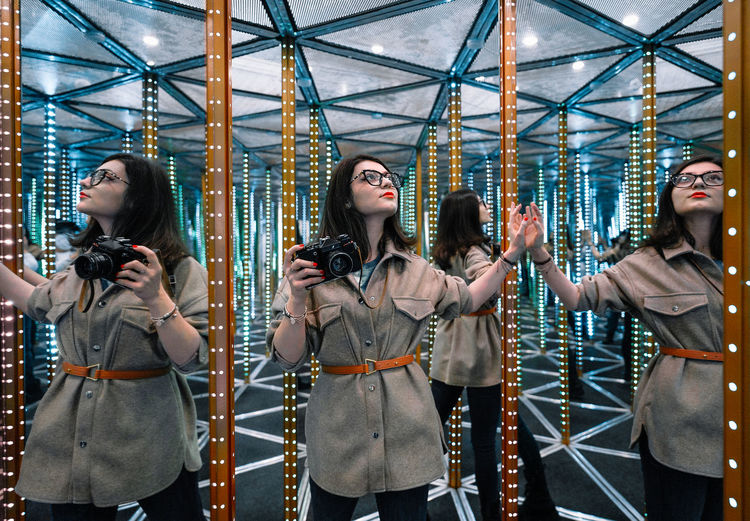 Young woman with camera in mirror maze