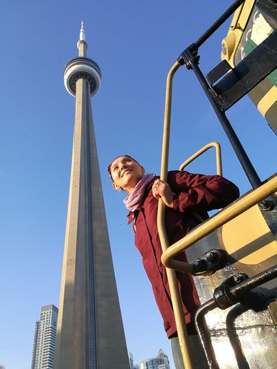 Smiling woman standing on vehicle against cn tower in city