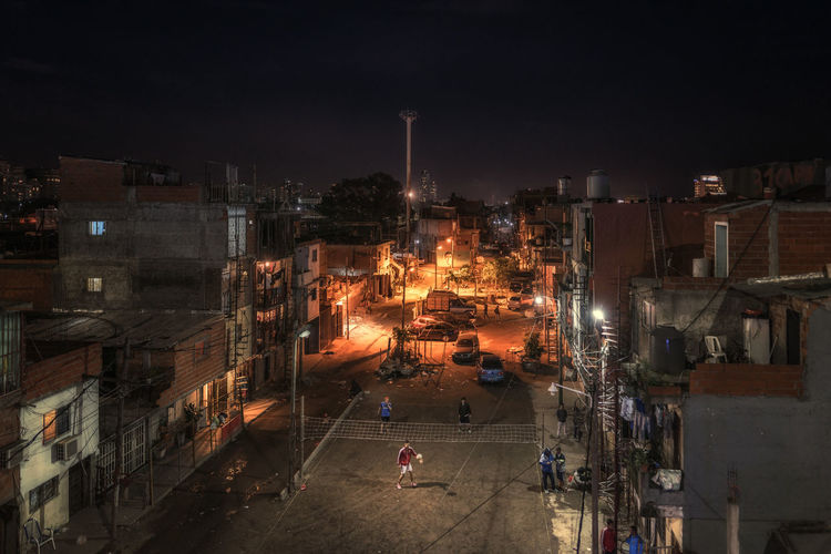 High angle view of people playing volleyball on street amidst residential buildings at night