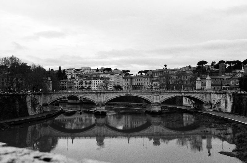 Bridge over river in city against sky