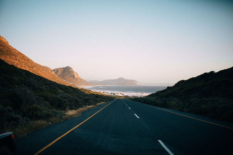 Empty road amidst mountains against clear sky