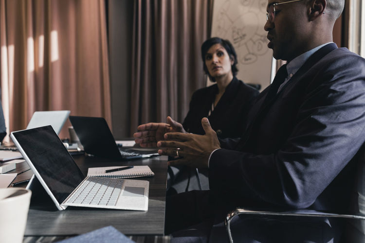 Businessman discussing with female colleague in board room during meeting