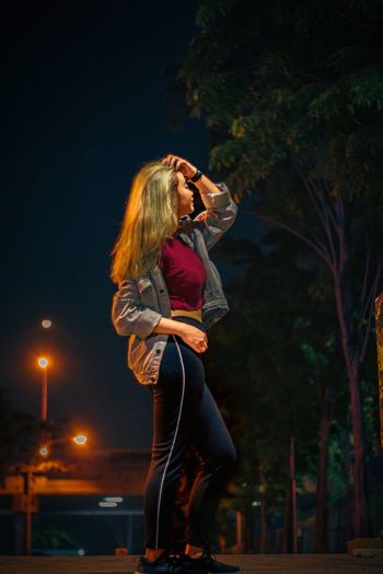 Side view of woman photographing illuminated at night