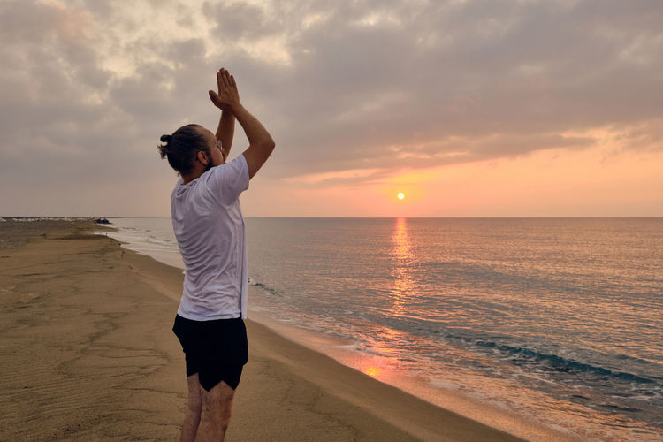Full length of man at beach against sky during sunset