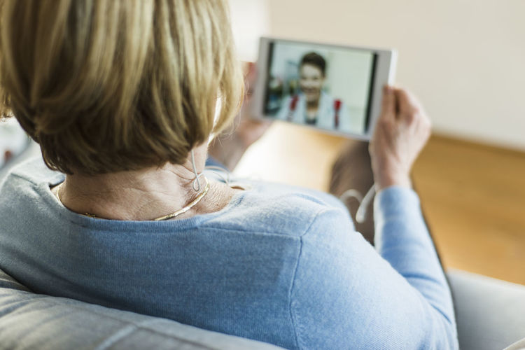 Senior woman looking at picture of young man on digital tablet