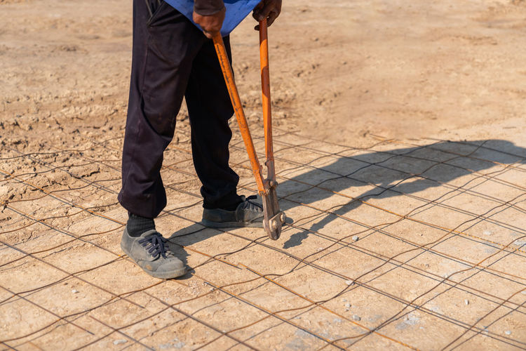 Worker cutting grating with plier cutter tool at construction site