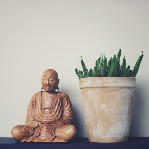 Close-up of buddha statue on table against wall