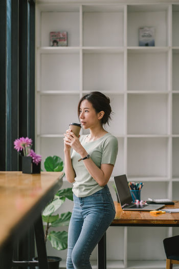 Woman drinking coffee while standing in office