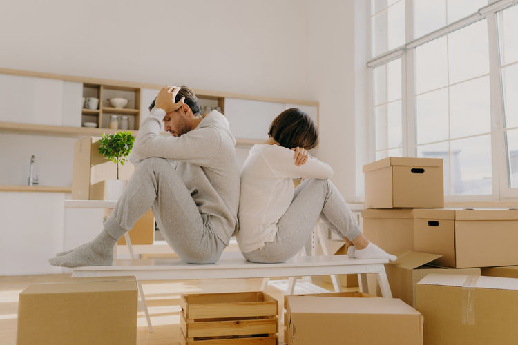 Couple sitting back to back while sitting on table at home
