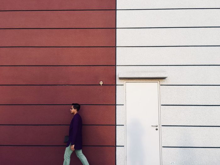 Side view man walking by wall outdoors