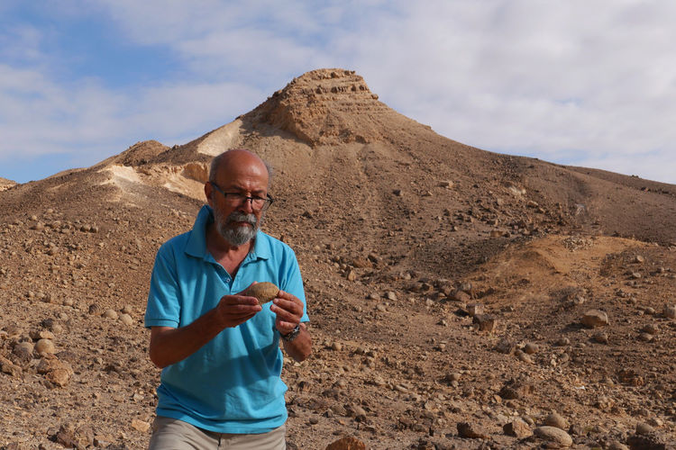 Senior man showing fossil in the desert 
