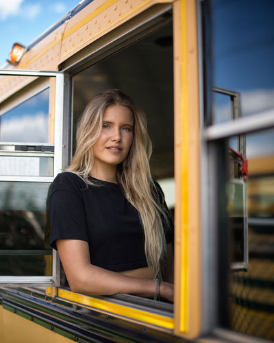Portrait of smiling young woman sitting in bus seen through window