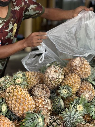 Midsection of man holding pineapple for sale