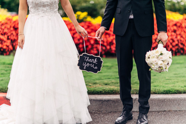 Low section of wedding couple with message standing on street