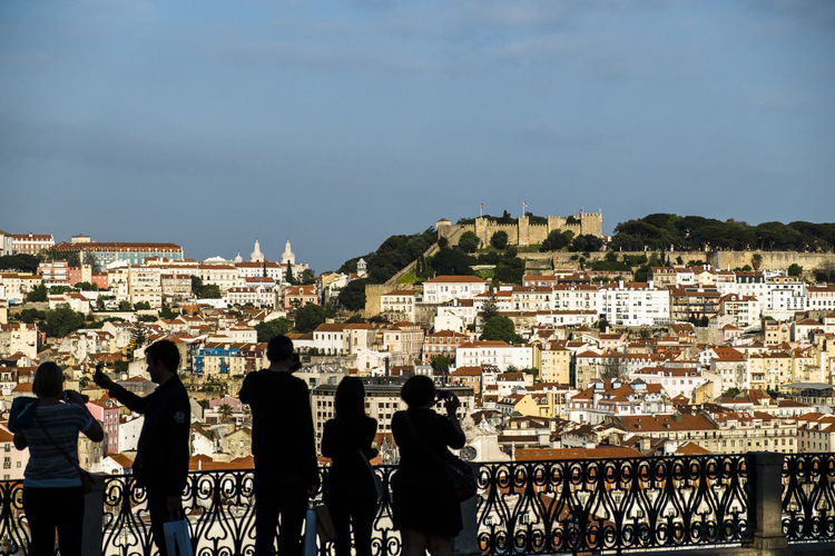 Rear view of people standing at observation point against castelo sao jorge