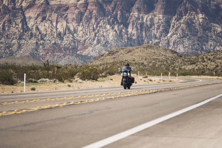 Man riding motorcycle on highway against mountain, nevada, usa