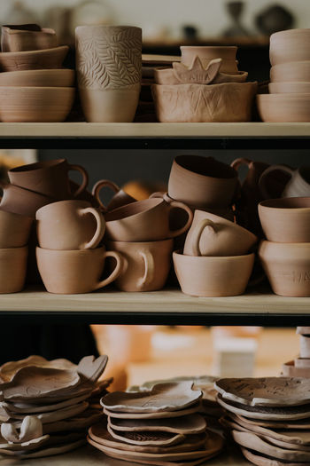 Shelves with ceramic dishware in pottery workshop