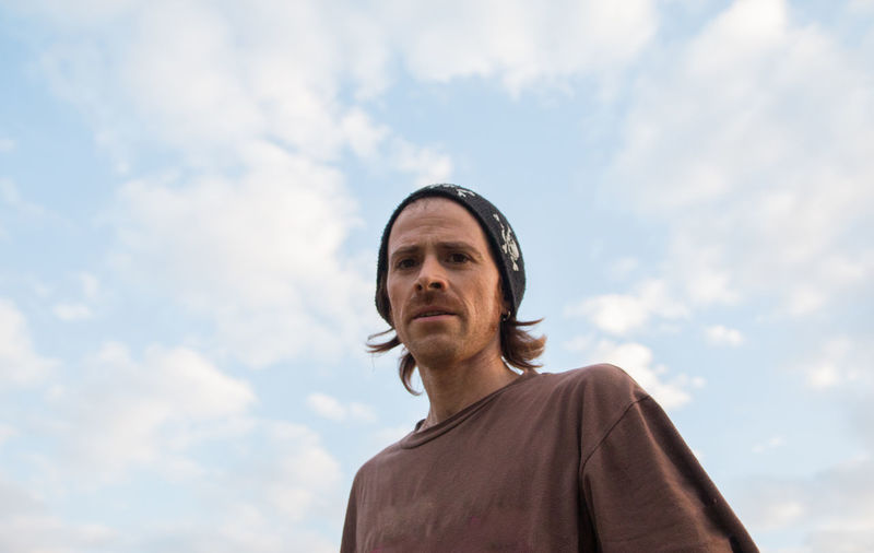 Portrait of trendy man against cloudy sky