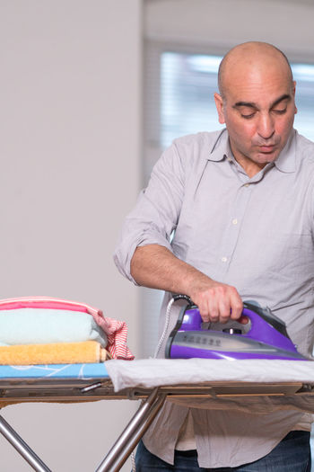 Man ironing clothes at home