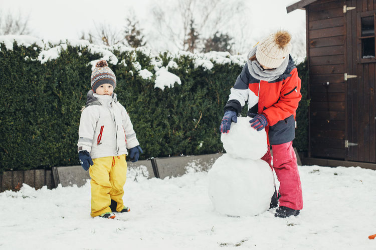 Snow time, games in the snow. winter holidays. caucasian children brother and sister make snowman