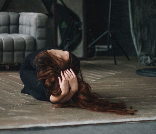 Woman with hand in hair kneeling on floor at home