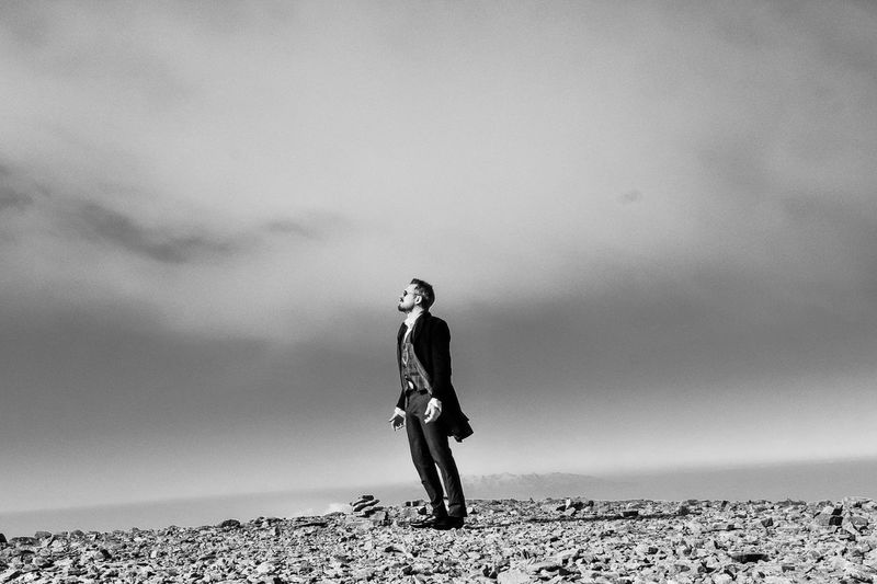 Full length of young man standing on beach against sky