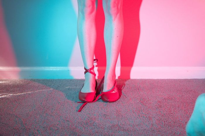 Low section of woman in red shoes standing against wall