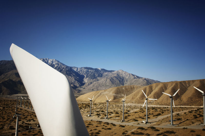 Wind turbines on field against clear blue sky