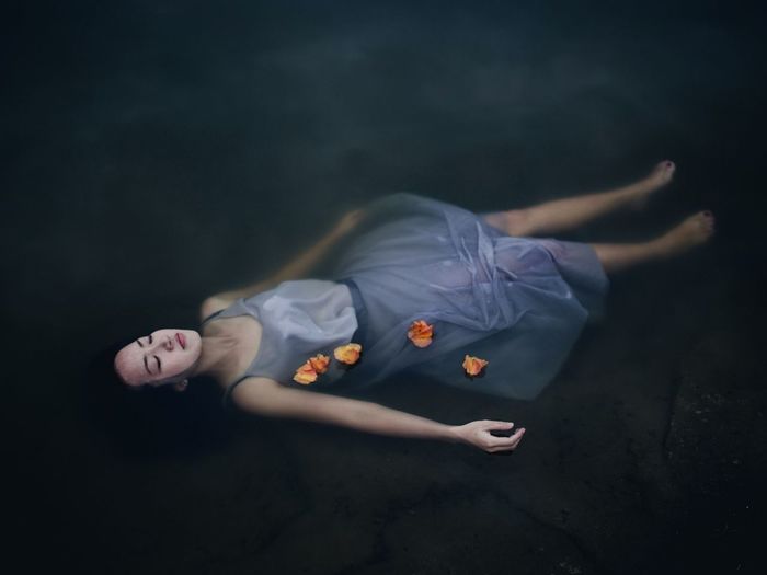 High angle view of young woman with eyes closed floating on lake