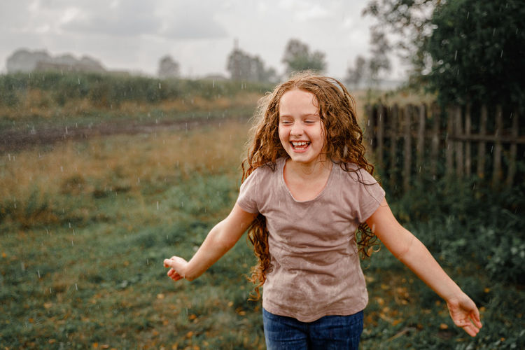 Laughing child spread its arms and catches raindrops. freedom, happy childhood