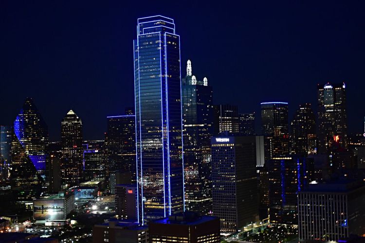 Illuminated cityscape against blue sky