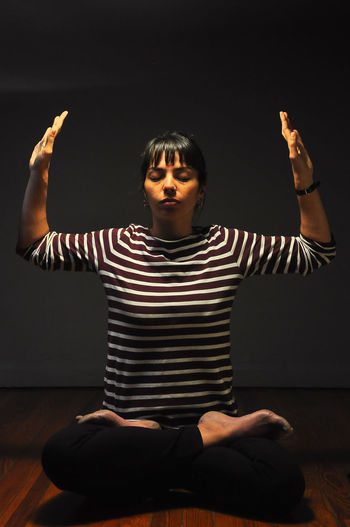 Woman meditating while sitting on floor at home