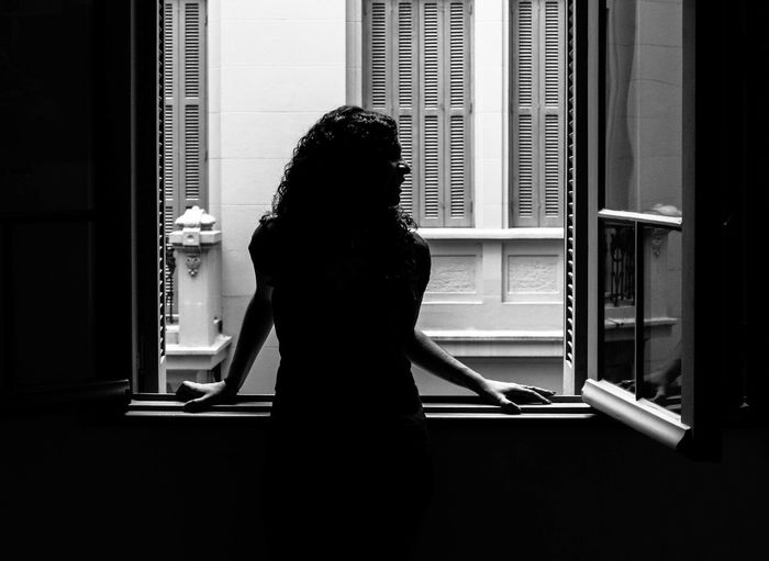 Young woman standing by window in apartment