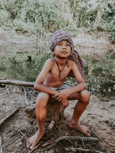 Full length of boy sitting against trees