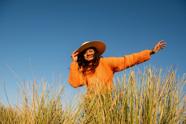 Woman wearing hat standing on field against sky
