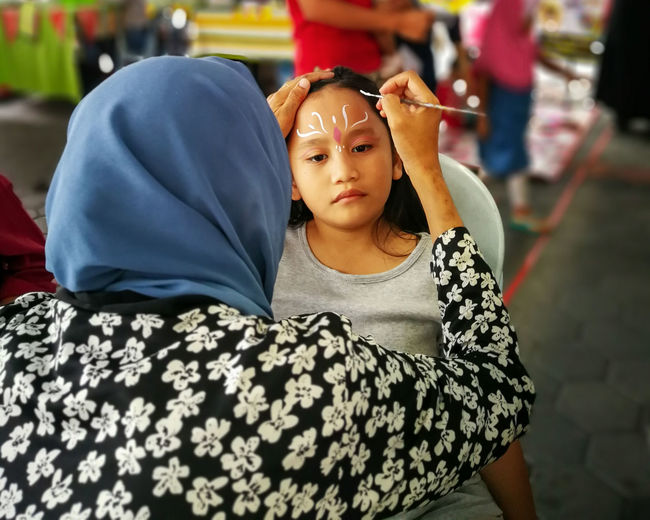 Children face painting. artist painting little girl at the shop.
