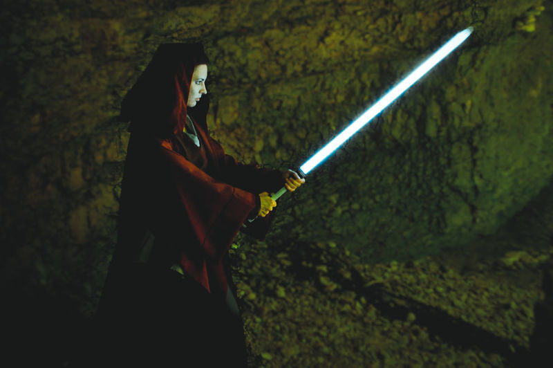 Side view of woman holding sword in cave