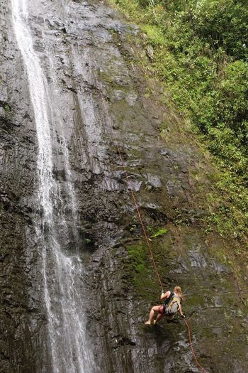 Woman standing on cliff by waterfall
