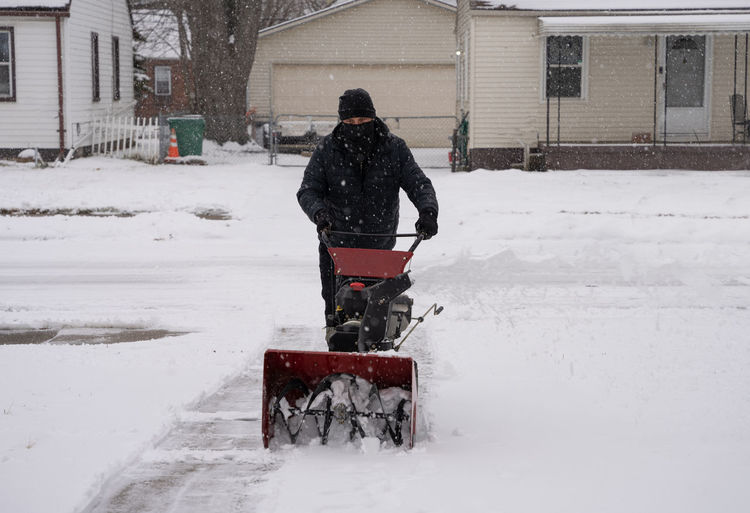 Man snowblows a driveway to clear the path after a heavy snow storm