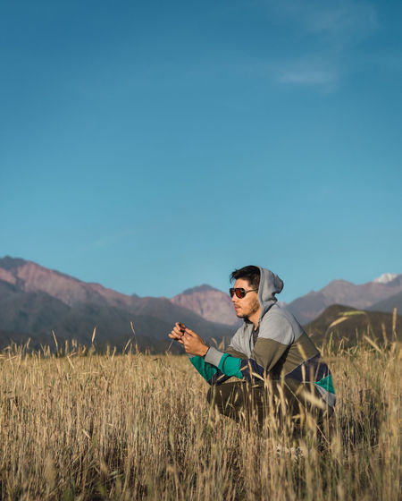 Young man sitting in a field next to the andes mountains