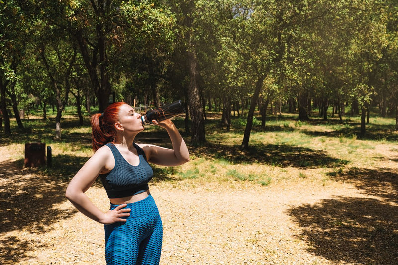Female athlete drinking water at park