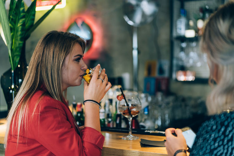 Blonde girl drinking in a bar.