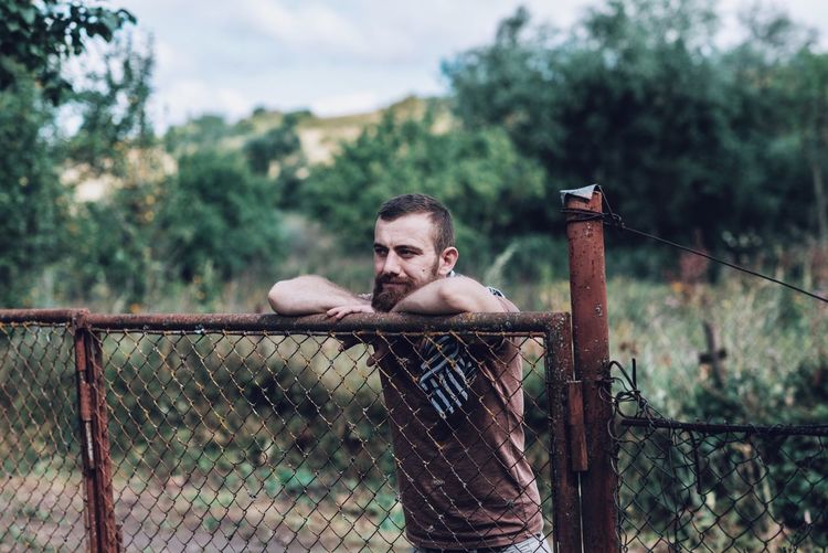 Man leaning on rusty fence