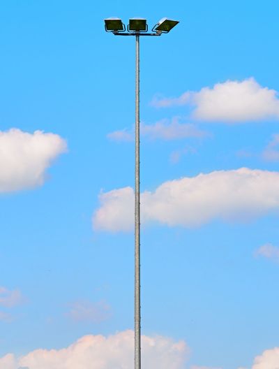 Tall steel lamp in the park on blue sky in background. high stadium light, spot light pole