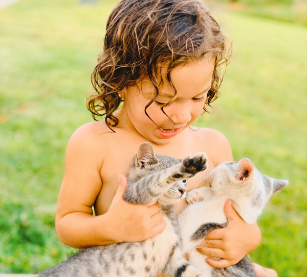 Cute shirtless girl playing with kittens at lawn