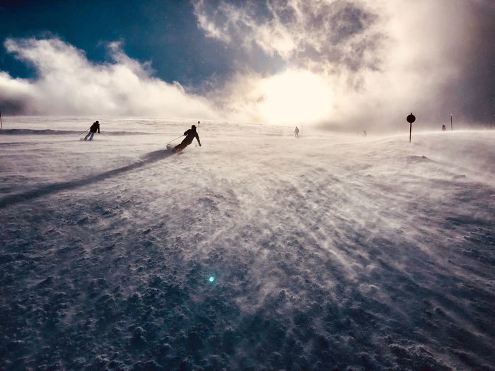 People on skiing on snow covered land against sky