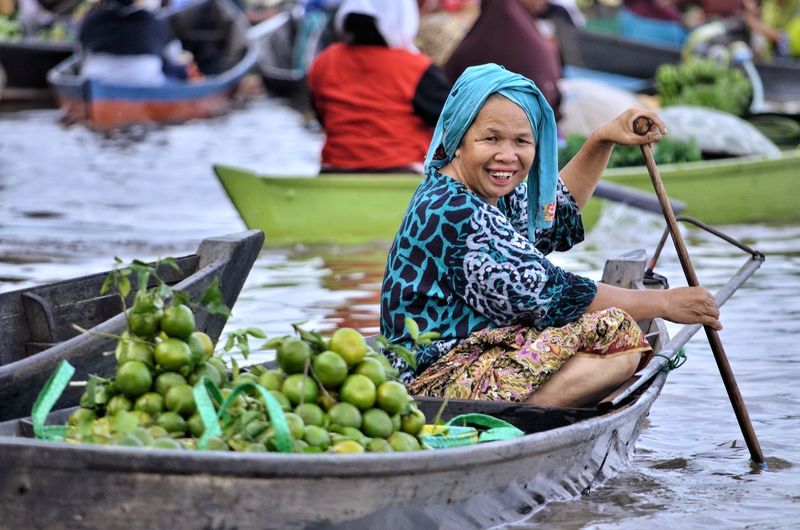 Full length of smiling woman sitting in boat